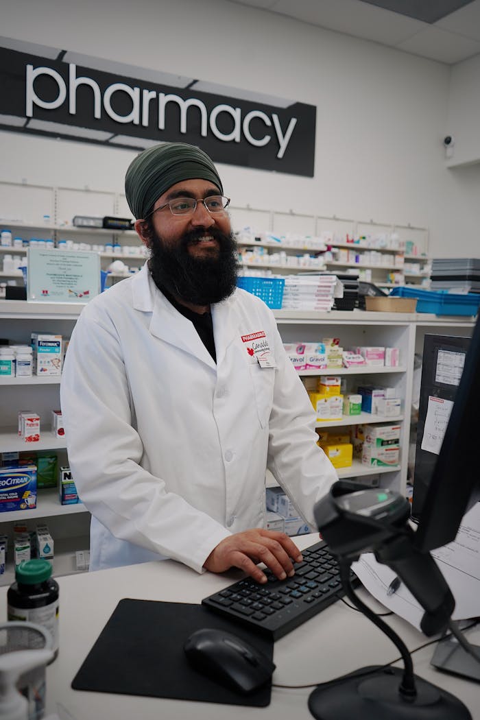 Smiling pharmacist with a turban assisting at the pharmacy counter.