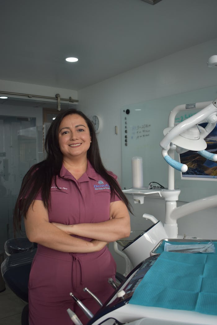 Female dentist standing confidently in a dental clinic, ready to assist patients with a smile.