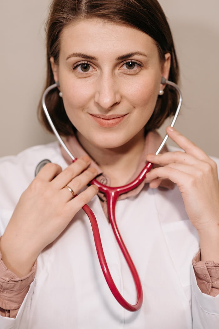 Portrait of a smiling female doctor holding a stethoscope indoors.